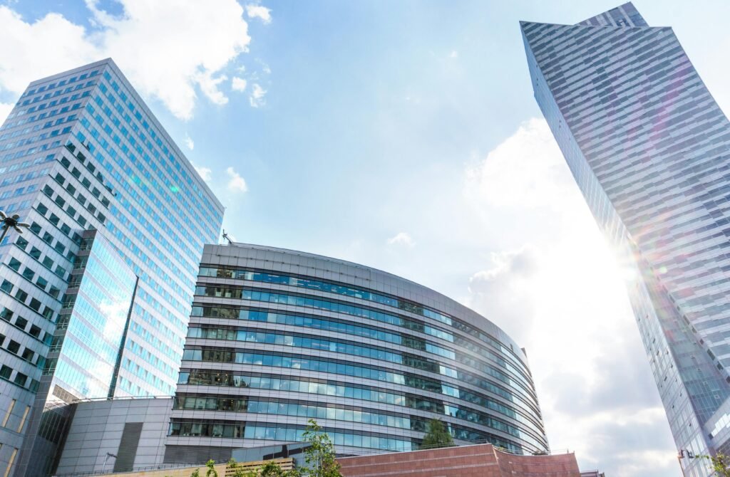 Urban cityscape with modern skyscrapers reflecting sunlight against a blue sky.
